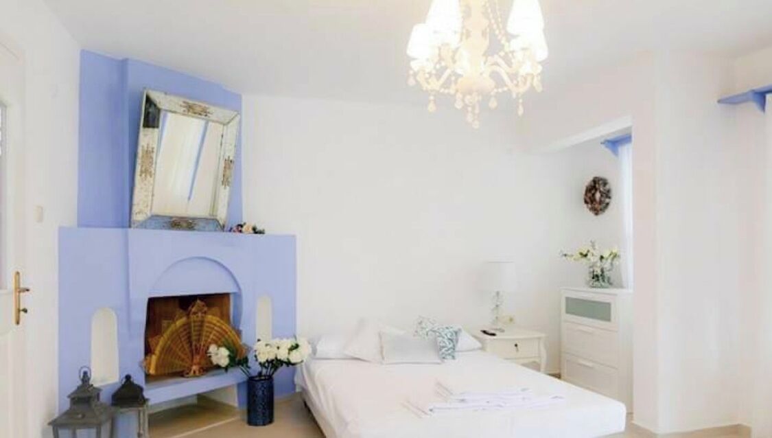 A bedroom with a fireplace, a bed, a nightstand, and a dresser.