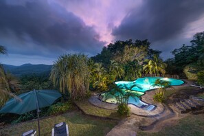 A swimming pool surrounded by tropical vegetation and a wooden deck. - Thebuwana Bungalow (Dodangoda)