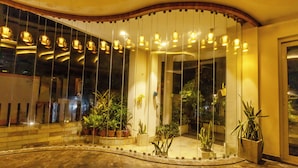 Espai interior ben il·luminat amb un mur corbat, plantes en testos i llums penjants.