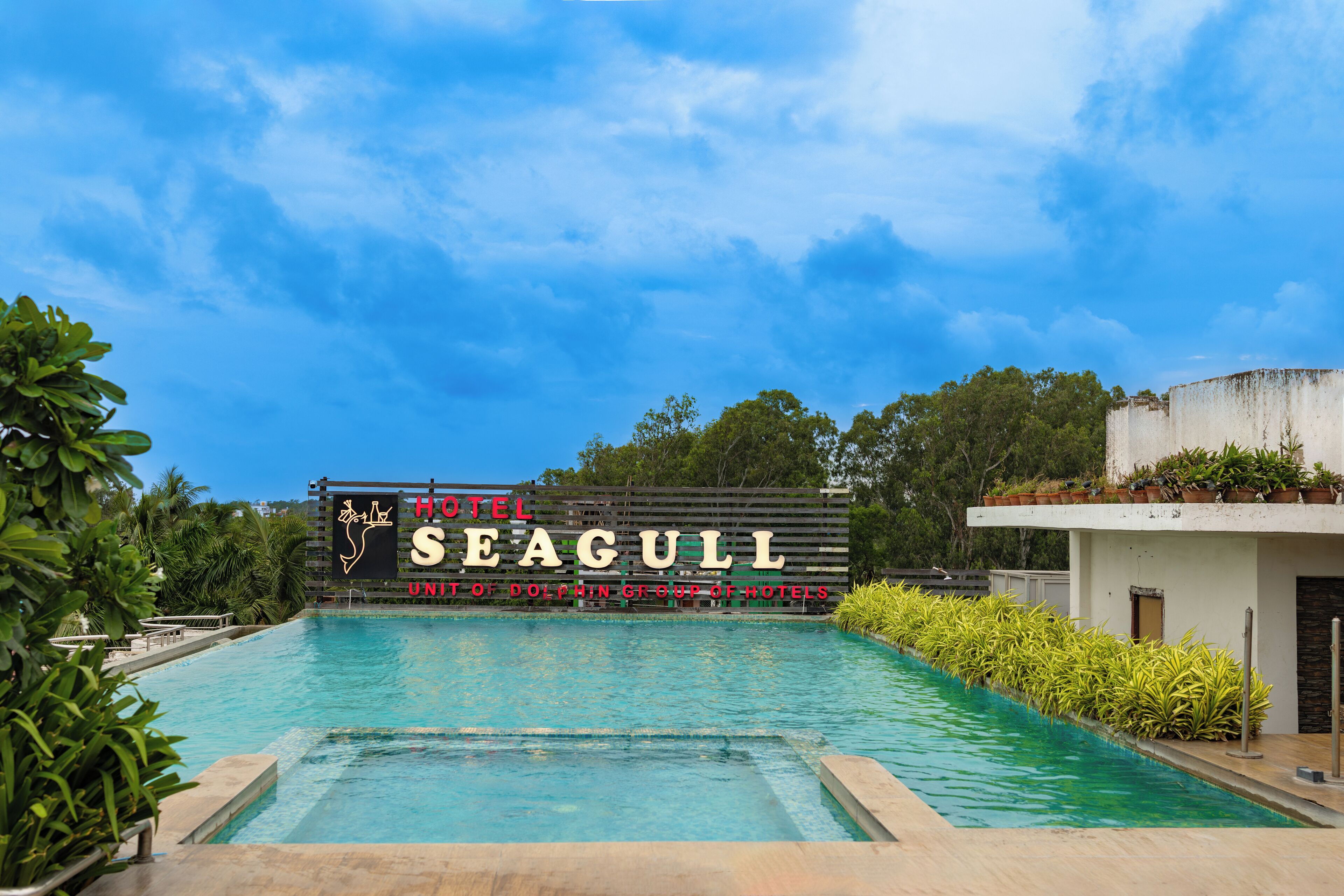 Placa de hotel com o nome 'SEAGULL' e área de piscina com água azul cristalina.