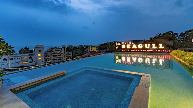 Una piscina d'hotel amb un cartell que diu "HOTEL SEAGULL" i vista a l'oceà.