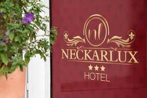 A maroon hotel sign with gold lettering and fleur-de-lis motifs. - Hotel Neckarlux (Heidelberg)