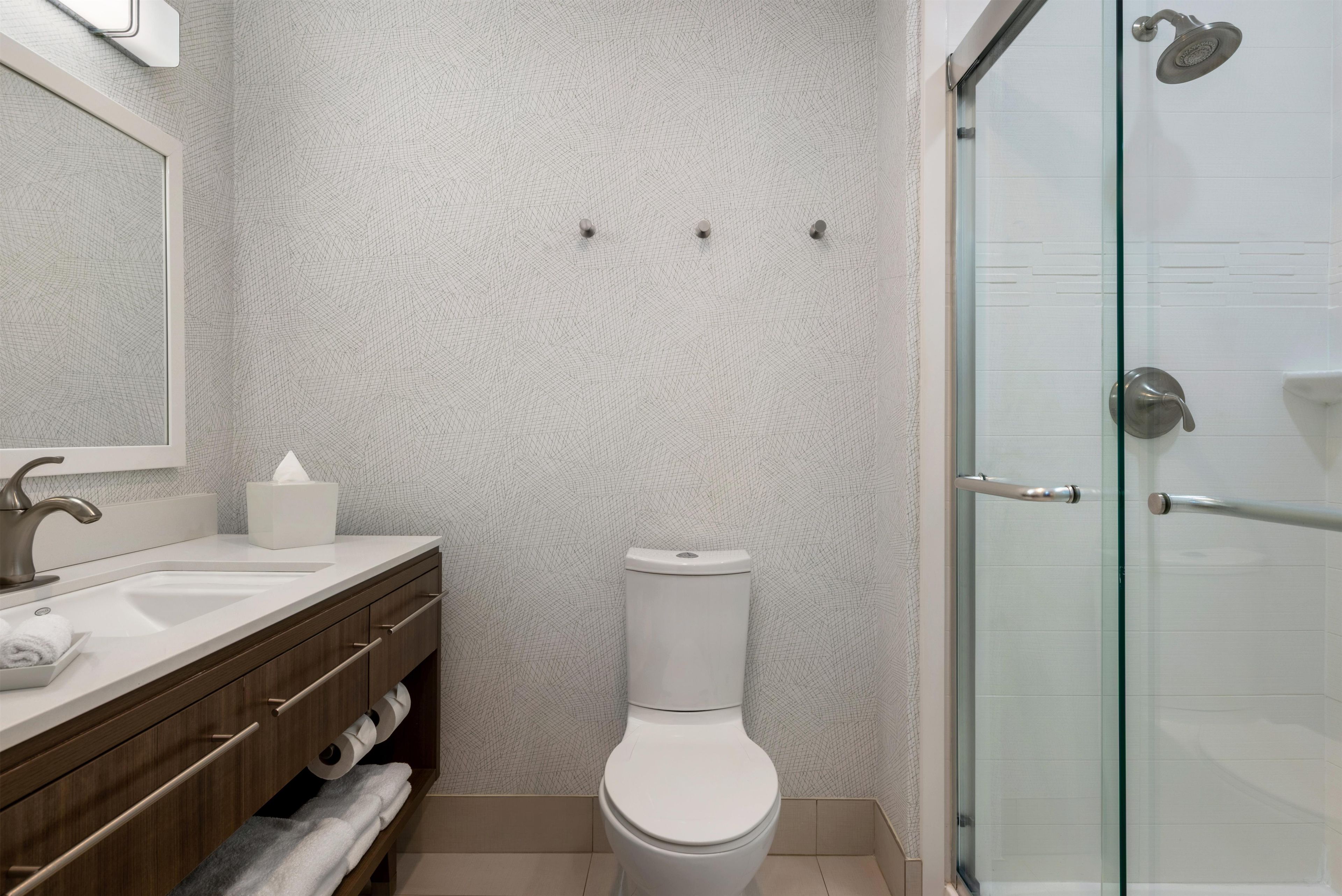 A bathroom with a white sink, mirror, toilet, and glass shower enclosure.