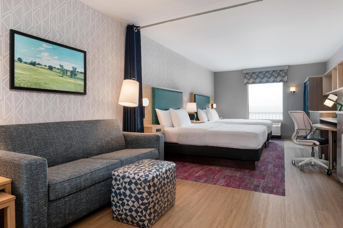 Une chambre d’hôtel avec un canapé, deux lits, un bureau et une chaise.