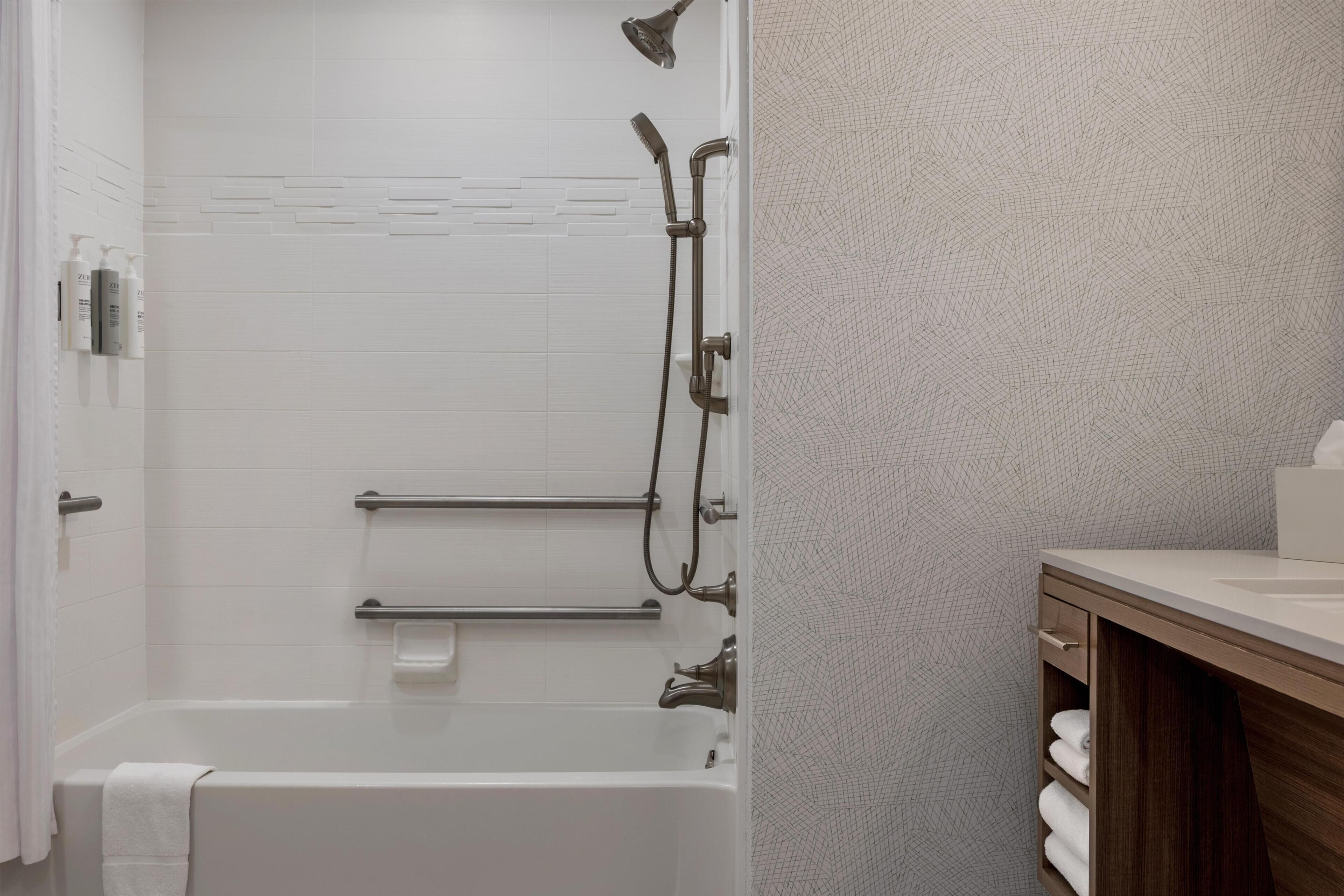 Une salle de bain moderne équipée d’une baignoire, d’une douche et d’un porte-serviettes.