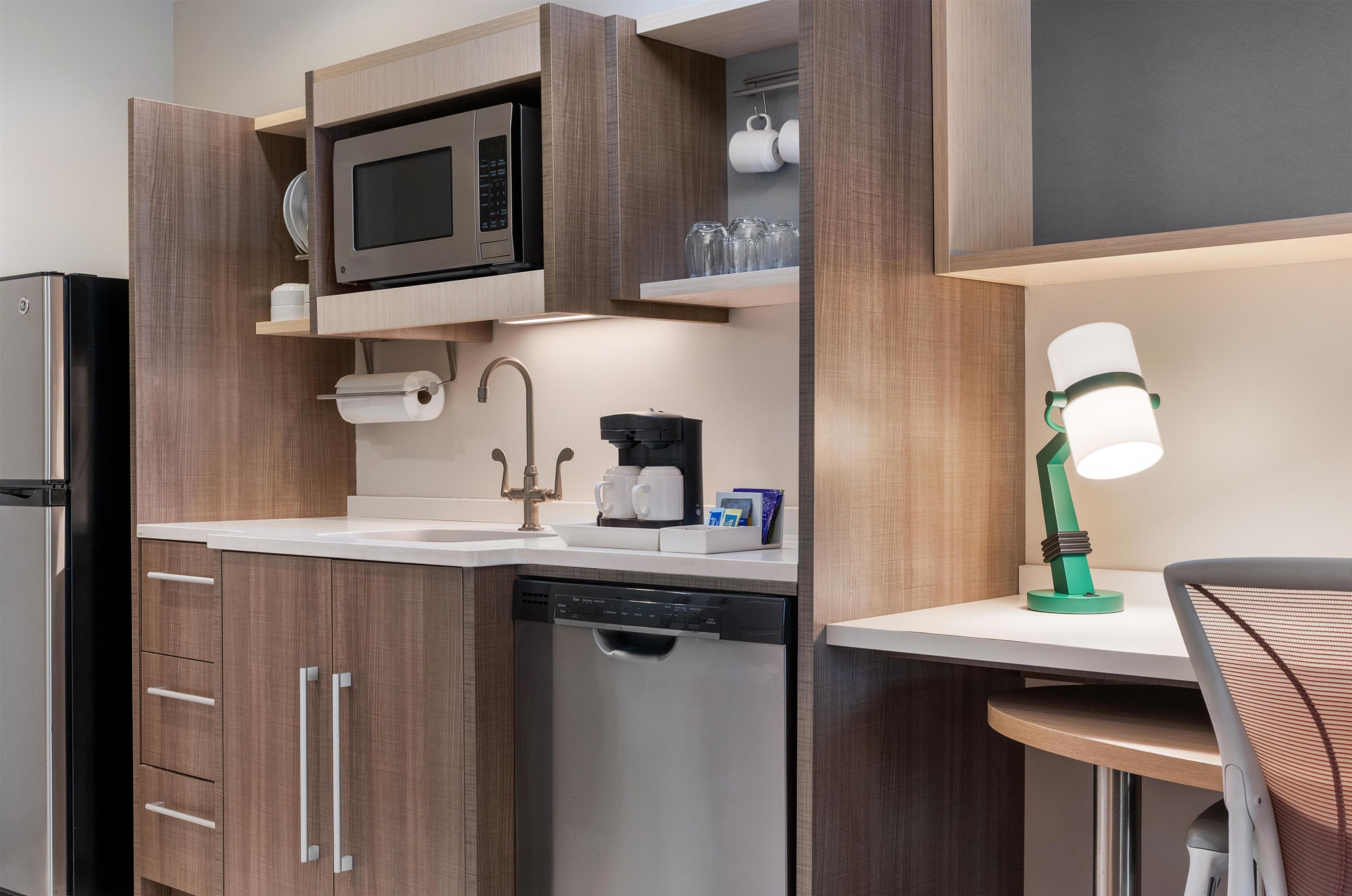 Uma cozinha compacta com micro-ondas, cafeteira e máquina de lavar louça.