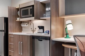 A compact kitchen with a microwave, coffee maker, and dishwasher.