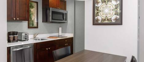 A modern kitchen with wooden cabinets, stainless steel appliances, and a dining area with a wooden table and chairs.
