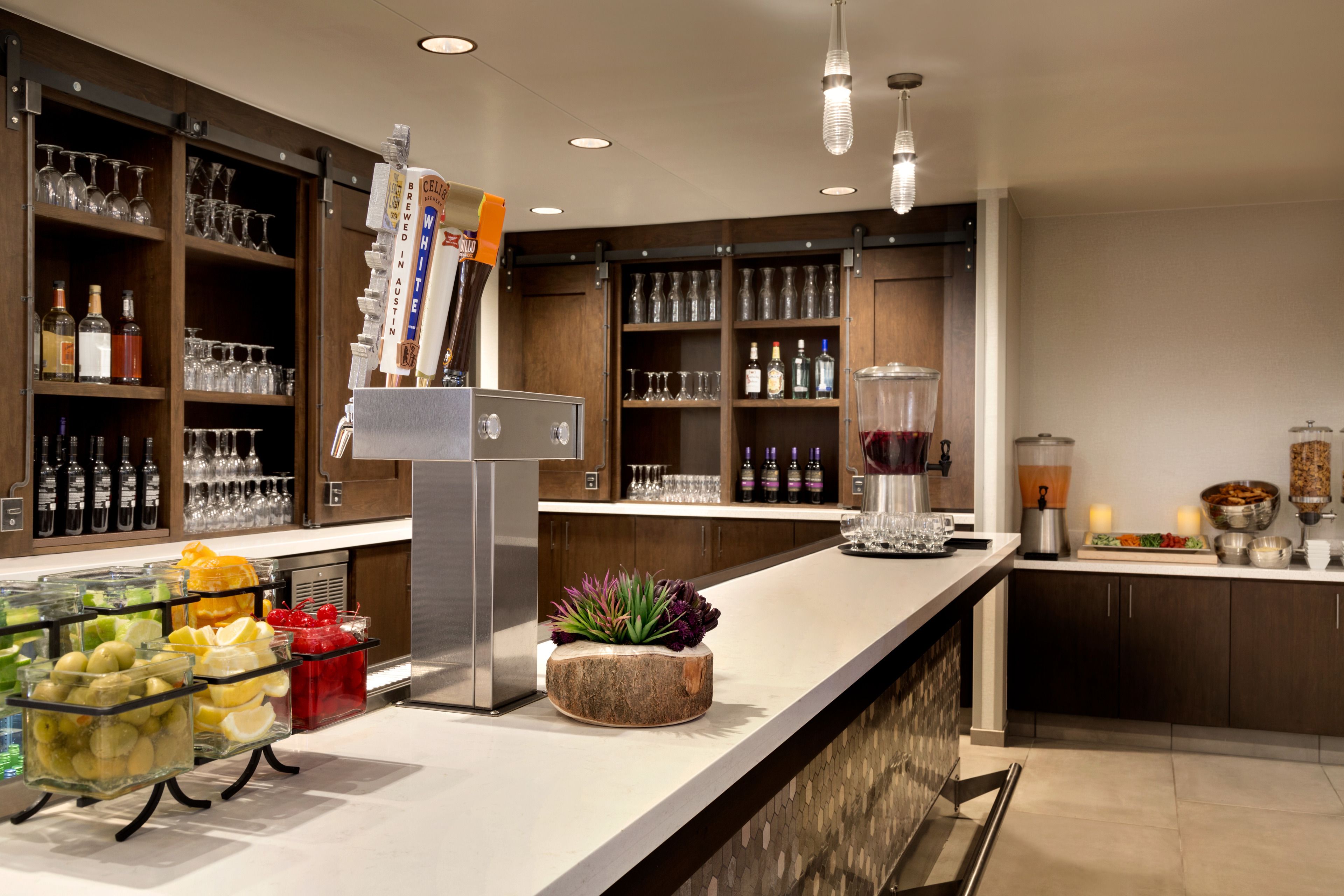 A bar area with shelves of bottles, glasses, and a fruit display.