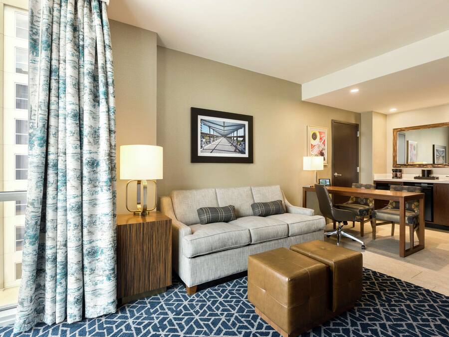 Ein Hotelzimmer mit einer Couch, Hocker, Esstisch und einer Küchenzeile.