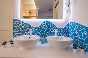 A bathroom with two white sinks, a blue mosaic backsplash, and small potted plants. - Paravia Suite (Florence)