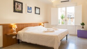 A hotel room with a bed, bedside lamps, a window with a view, and framed artwork on the wall. - Paravia Suite (Florence)