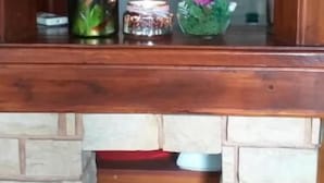 A wooden shelf with a green bottle, a candle, and a small vase with flowers. - Kolpinghaus (Caransebes)