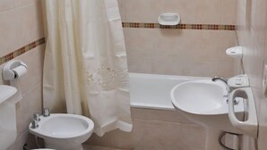Une salle de bain comprenant des toilettes, un bidet, un lavabo et une baignoire.