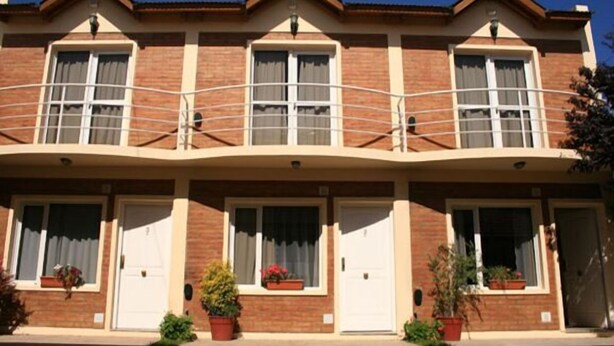Une rangée de maisons de ville à trois étages, dotées de balcons, de façades en briques et de plantes en pot.