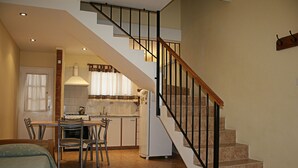 Une cuisine avec un coin repas, un escalier et un lit.