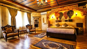 Un dormitorio espacioso con una cama grande, sillas ornamentadas y una chimenea.