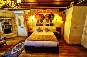 A traditional room with a large bed, a patterned rug, and a decorative wall with wall-mounted lights. - Empire Cave Hotel (Nevsehir)