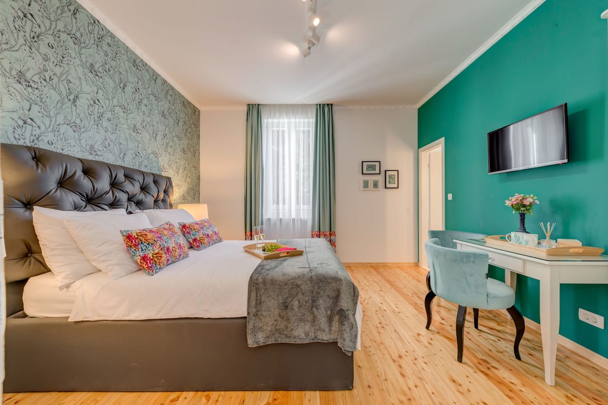 A bedroom with a large bed, a desk, and a TV.
