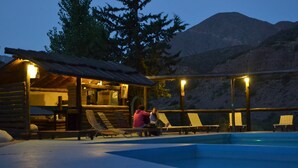 A log cabin with a pool and lounge chairs, surrounded by mountains. - Mendoza Sol y Nieve (Potrerillos)