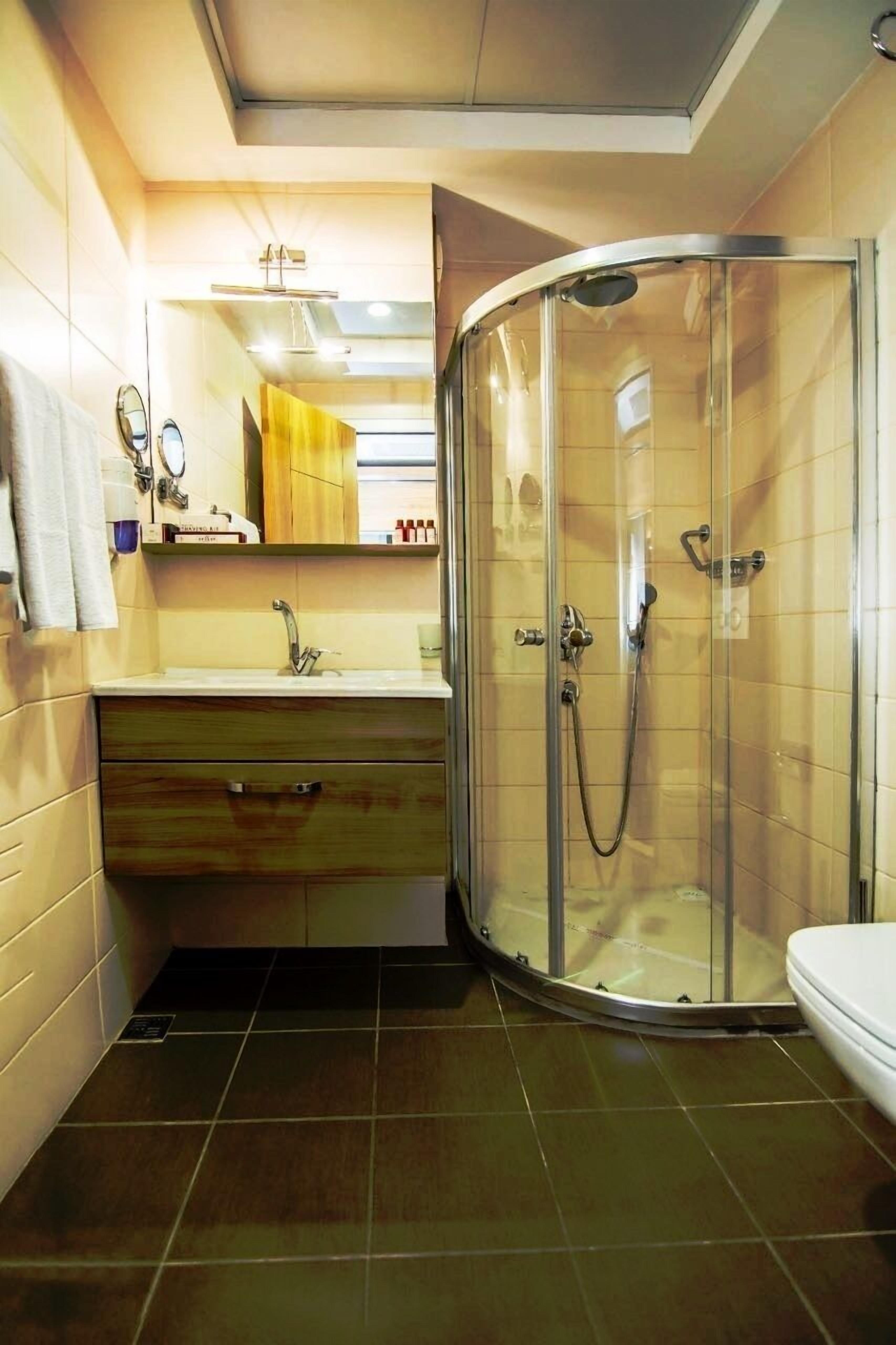 A modern bathroom with a glass-enclosed shower, a sink with a mirror, and a toilet.