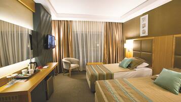 Habitación de hotel con dos camas, un escritorio, una silla, un televisor y una ventana con cortinas.