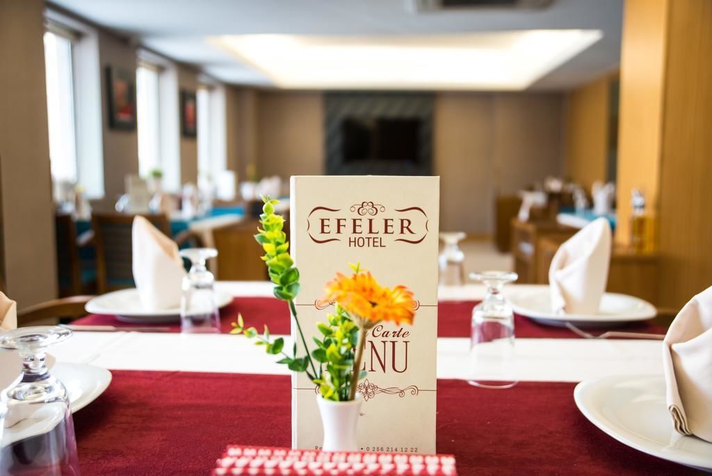 A hotel dining area with a menu stand displaying the name 'Efeiler Hotel' and a 'Carte Menu'.
