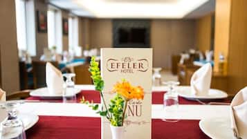 A hotel dining area with a menu stand displaying the name 'Efeiler Hotel' and a 'Carte Menu'.