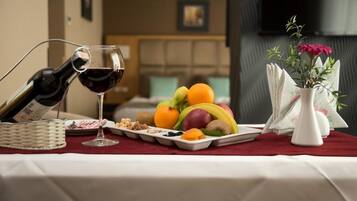 Un tavolo da pranzo con una bottiglia di vino rosso, un bicchiere e un vassoio di frutta.