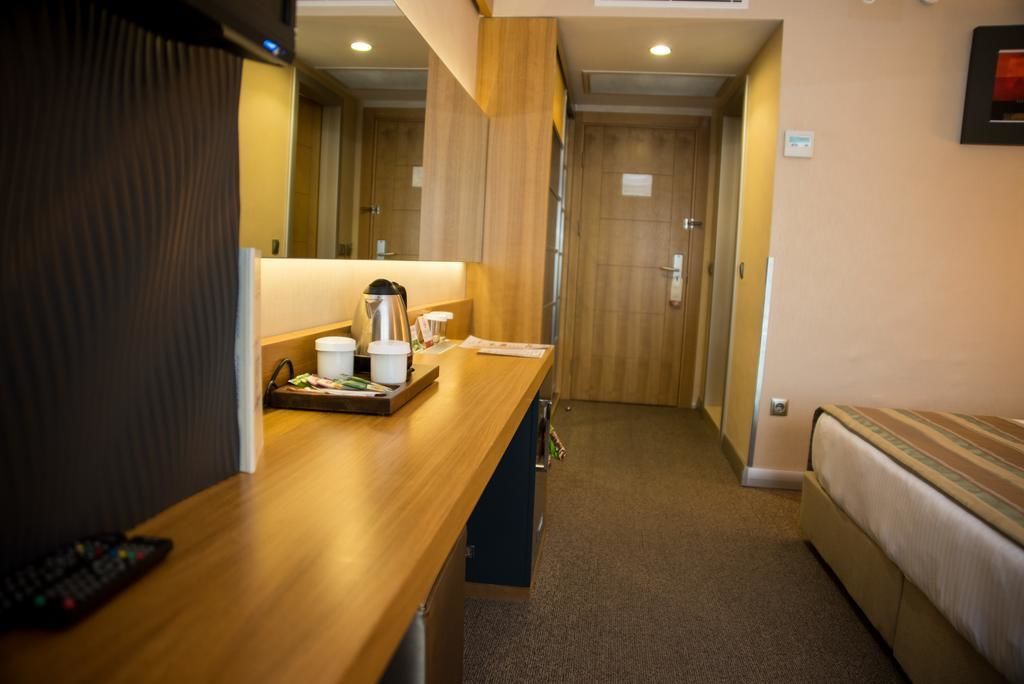 Una habitación de hotel con un escritorio de madera, una cama y una puerta que da a otra habitación.