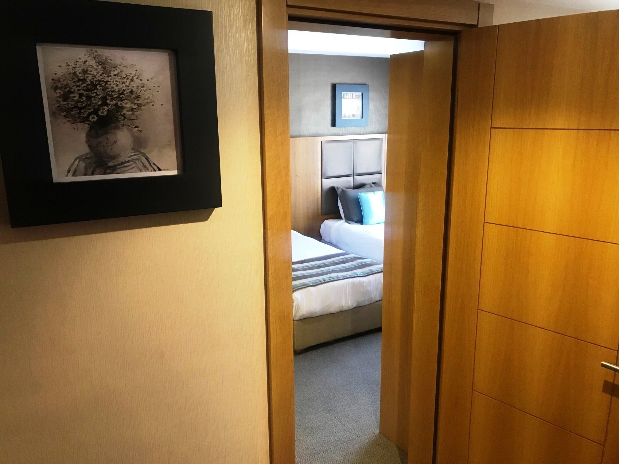A hotel room with a bed, a bedside table, and a framed picture on the wall.