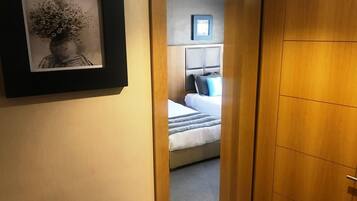 Quarto de hotel com uma cama, mesa de cabeceira e quadro na parede.