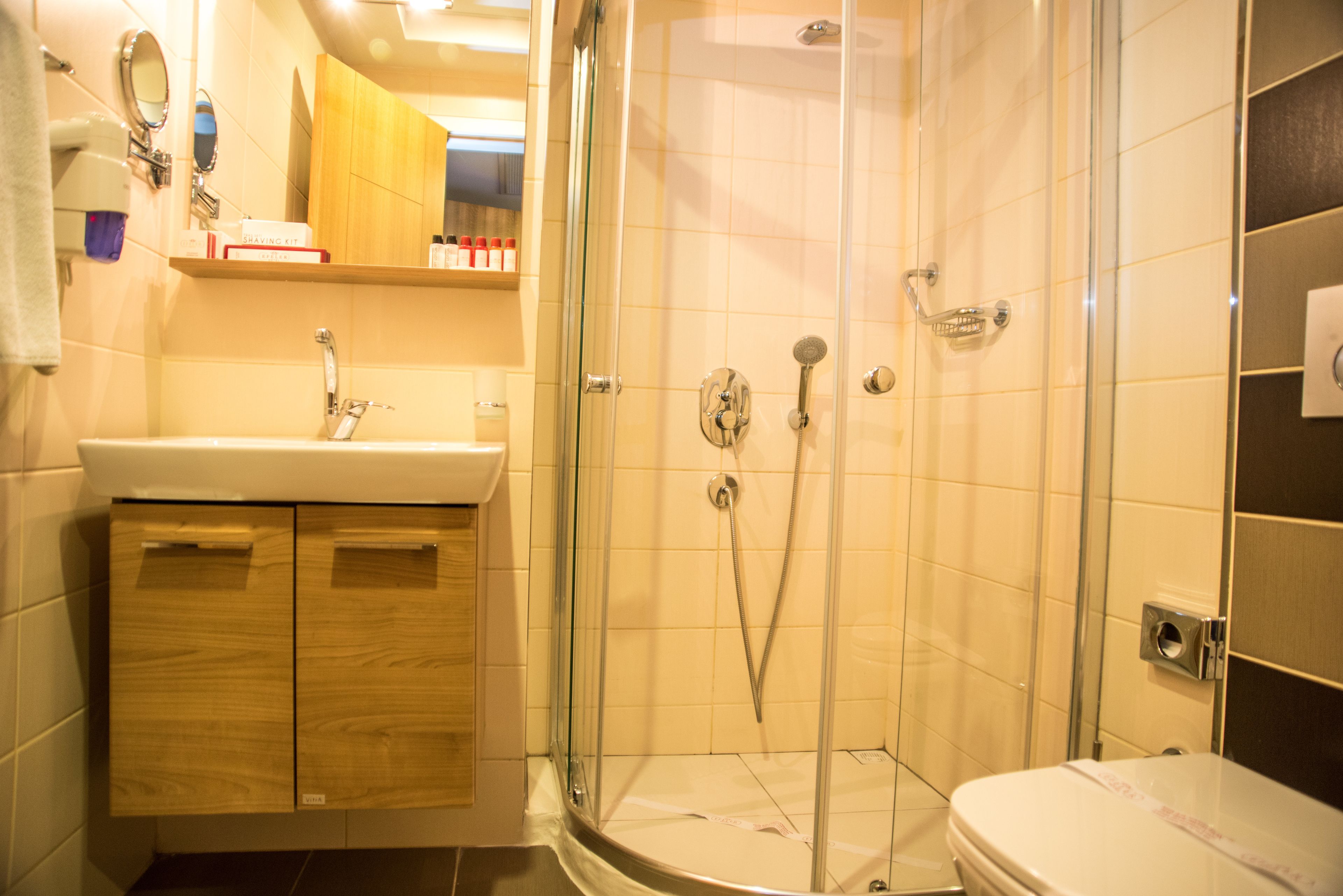 Un baño moderno con ducha de vidrio, tocador de madera y un inodoro.