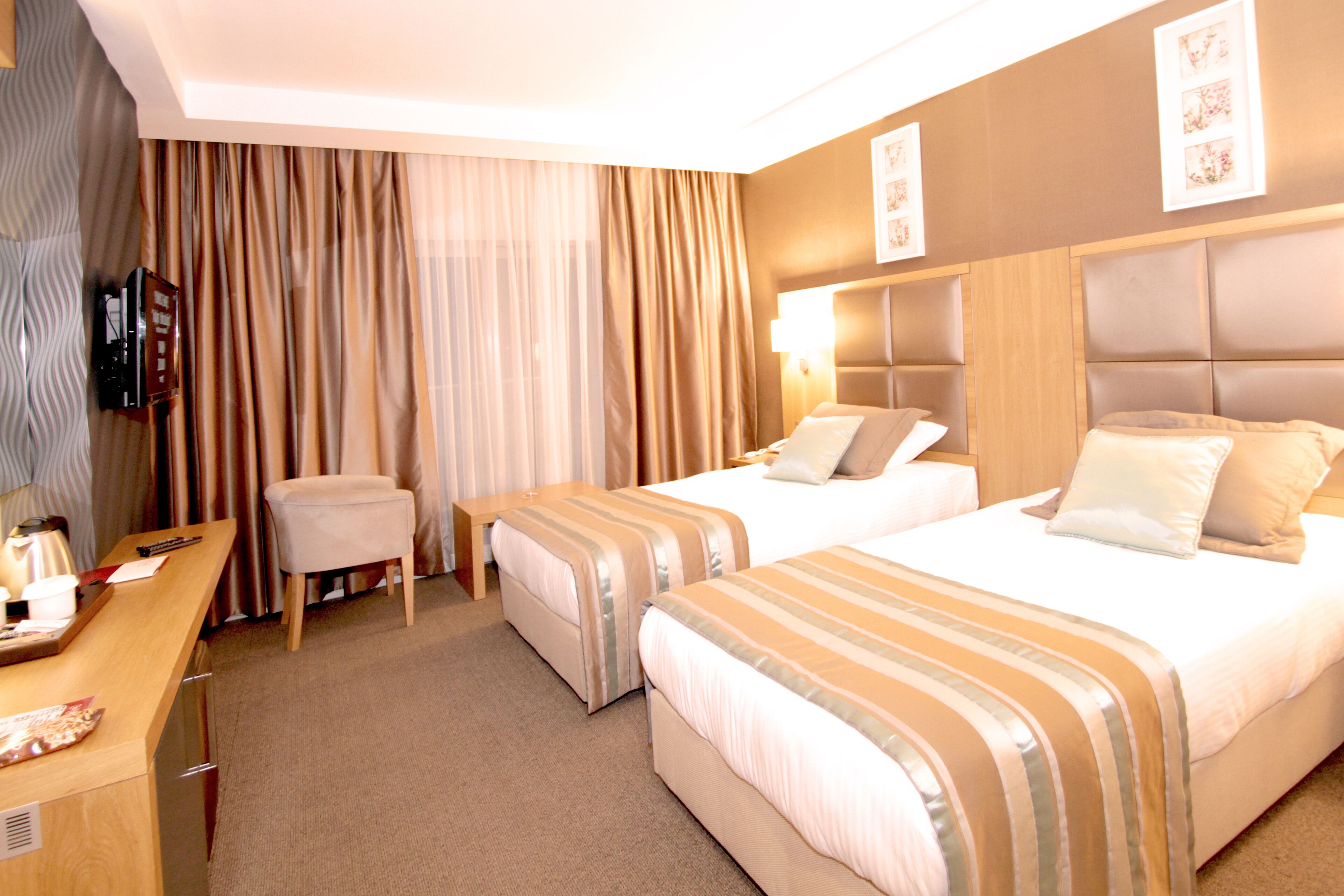 Une chambre d’hôtel avec deux lits, un bureau, une chaise et un téléviseur.