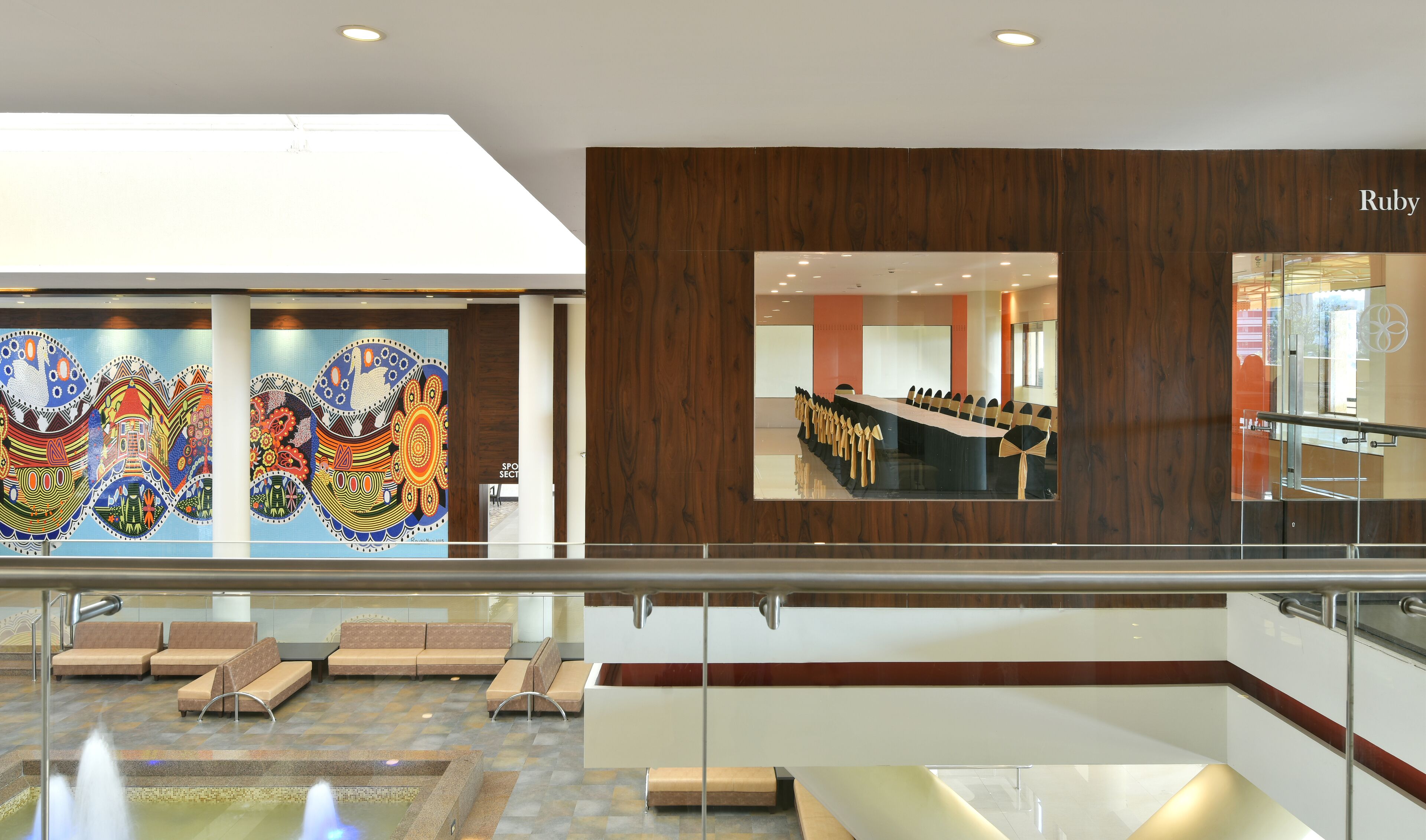 A modern lobby with a large meeting table, seating area, and a wall with colorful artwork.