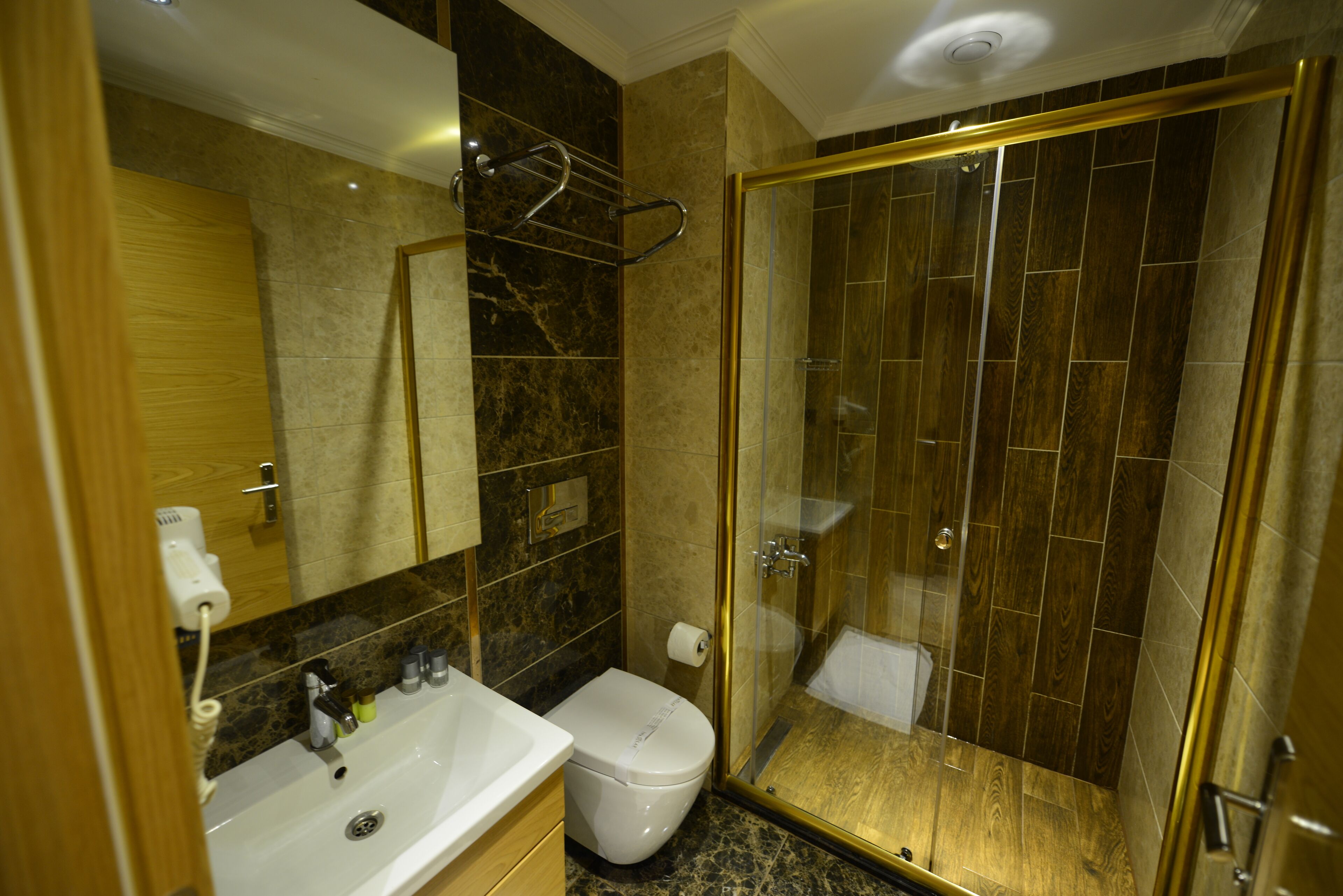 A bathroom with a marble sink, a toilet, and a glass-enclosed shower.