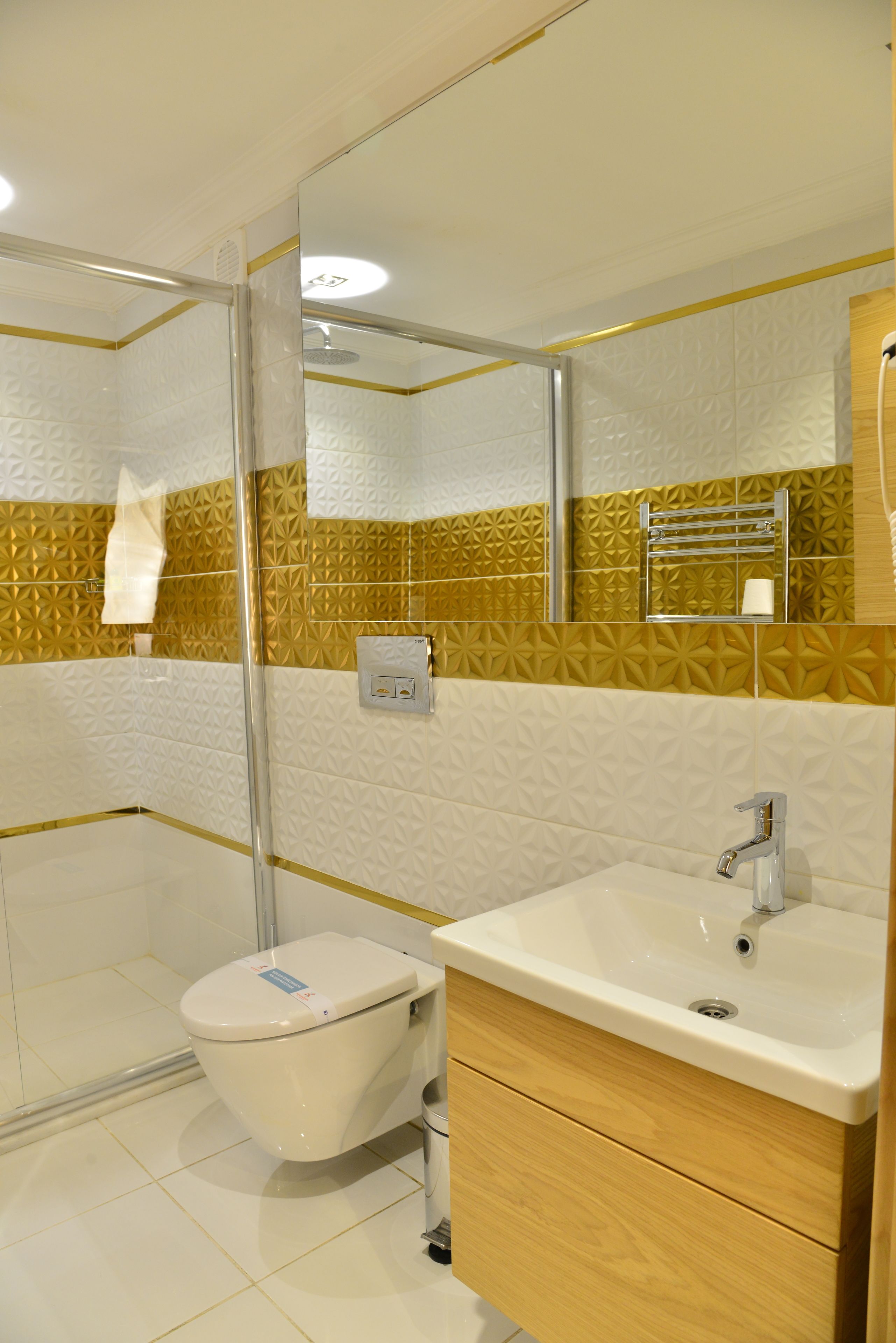 Et moderne badeværelse med bruseniche, toilet i hvidt og et træbord med vask.