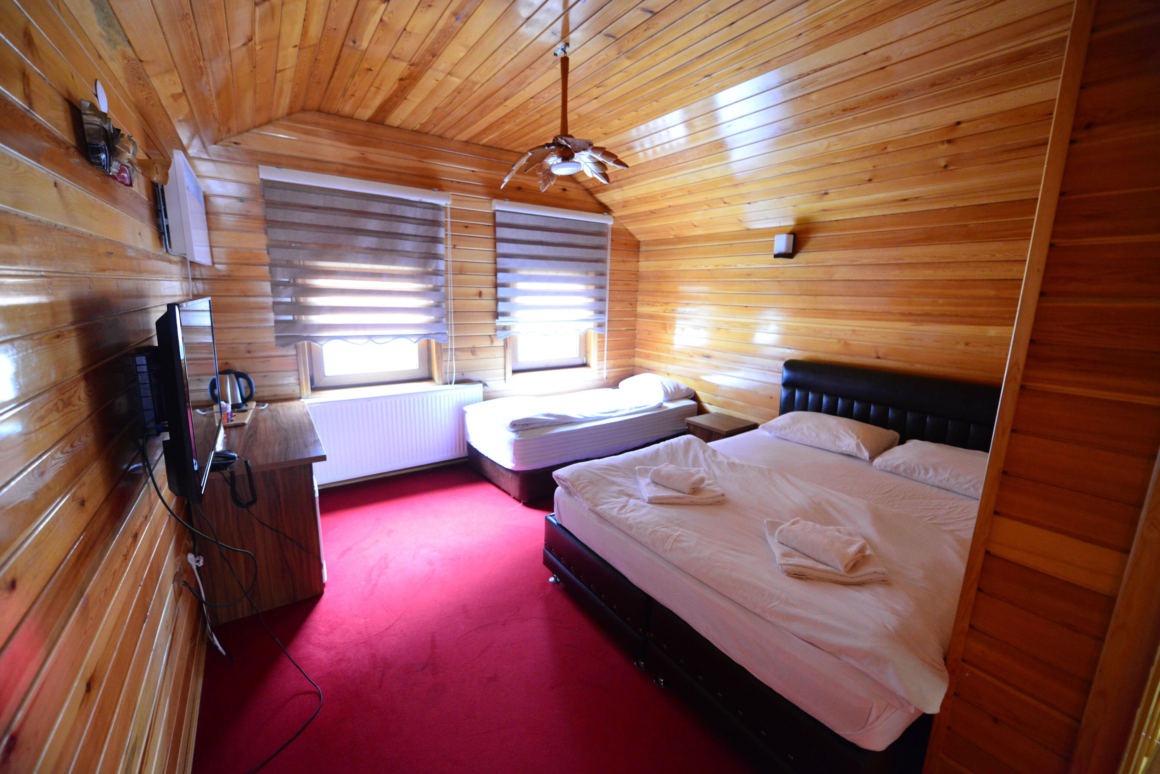 A wooden-paneled room with a bed, a desk, and a window.