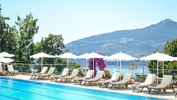 Una piscina al aire libre, sombrillas, sillones reclinables de piscina