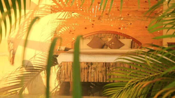 Techo de madera con una cama, almohadas y una mesita de noche.