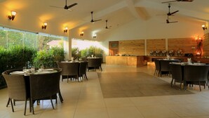 Un restaurante con varias mesas y sillas, ventiladores de techo y una zona de bar de madera.