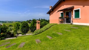A house with a sloped roof, a balcony with potted plants, and a view of the countryside. - Agriturismo Al Colle (Cavaion Veronese)
