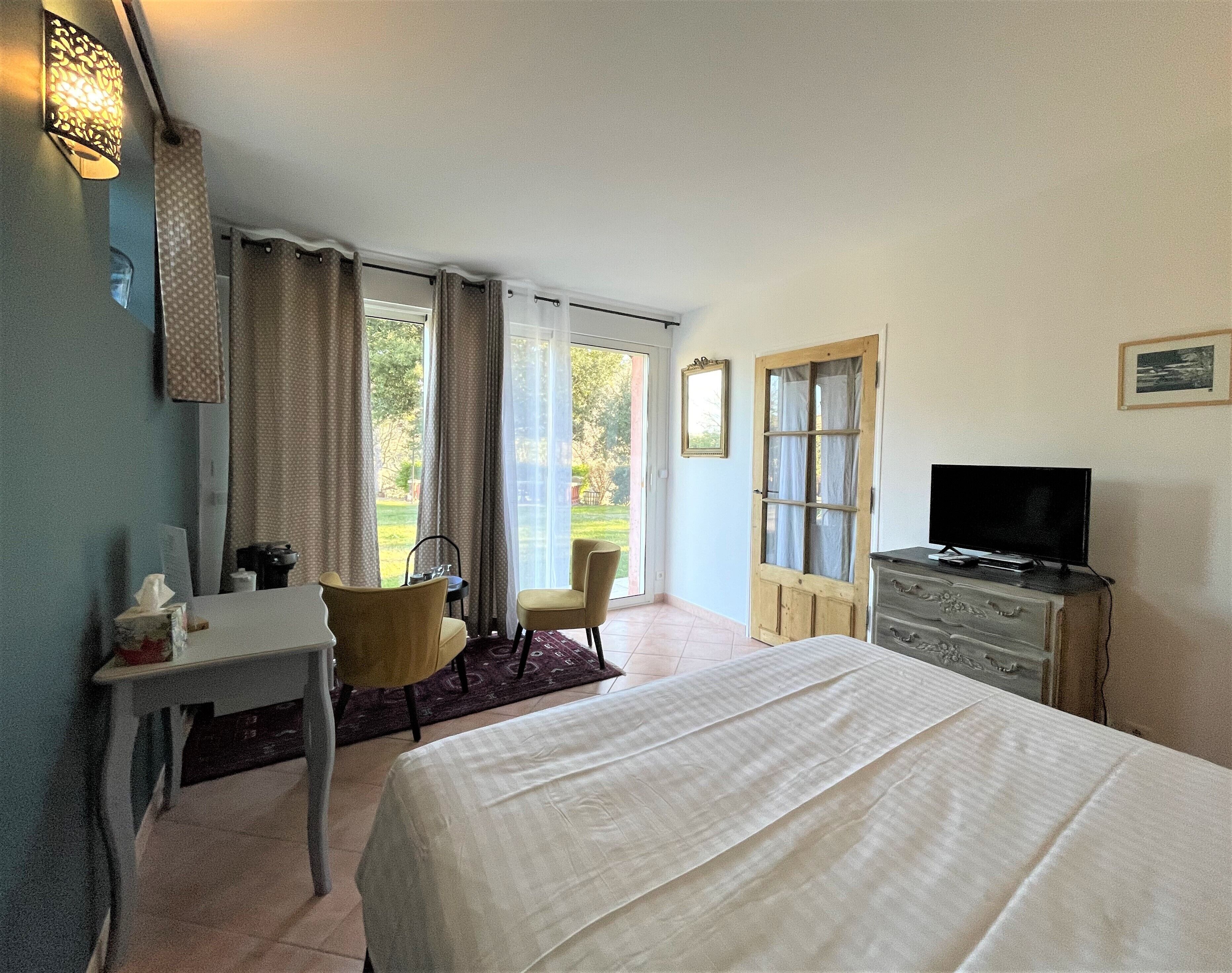 Ein Hotelzimmer mit Bett, Schreibtisch, Sessel, Fernseher und Kleiderschrank.