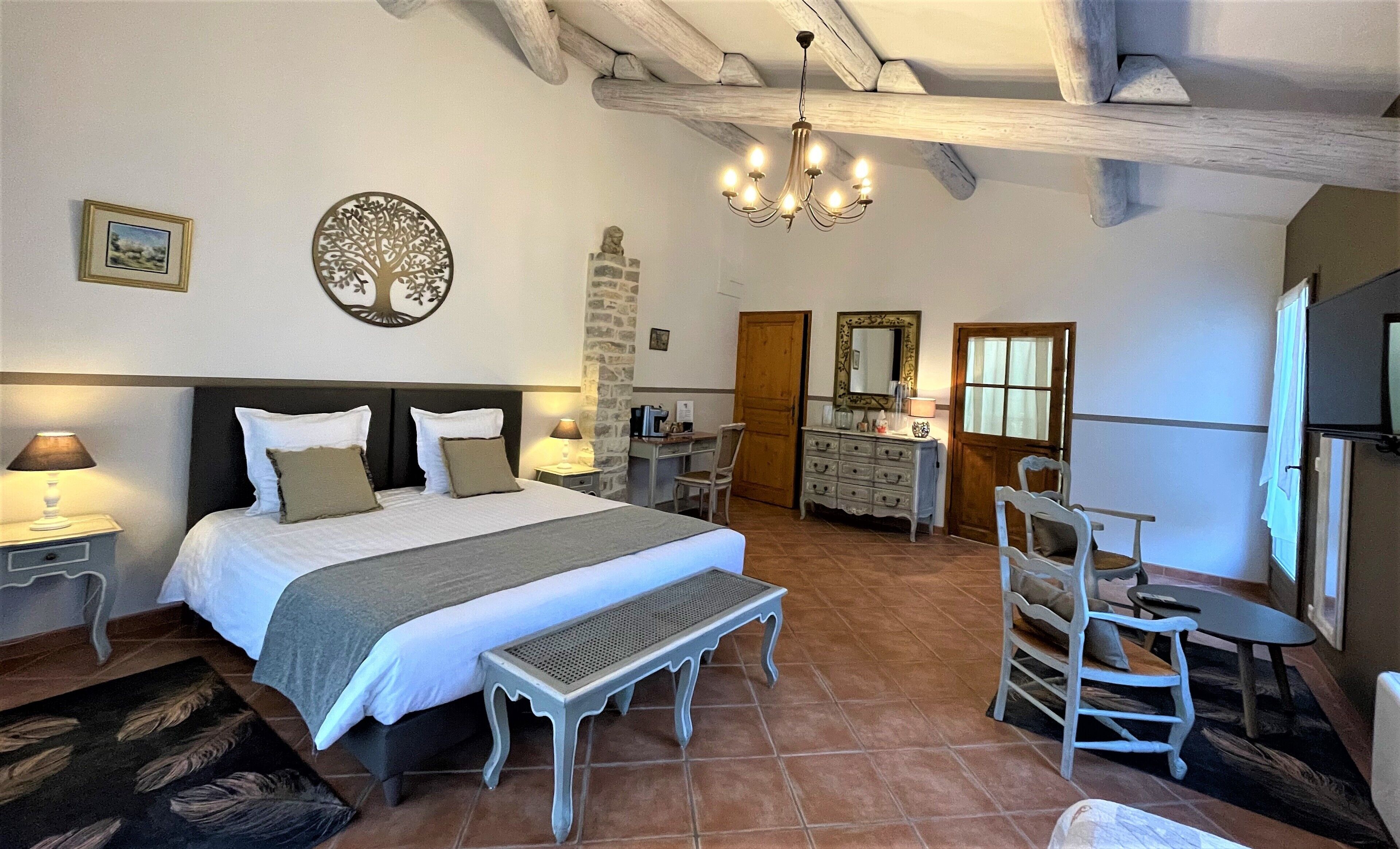 A bedroom with a large bed, a bench, a dresser, and a chair.