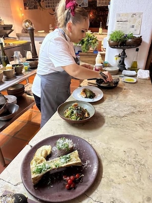 Un chef preparando comida en una cocina con varios platos y utensilios de cocina sobre la encimera.