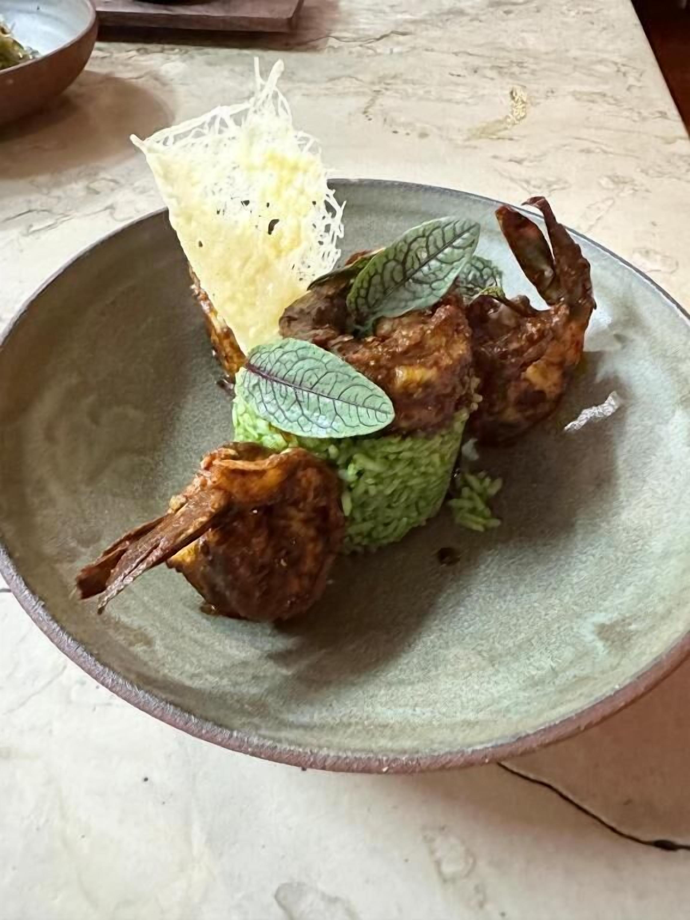 A plate with a food item, possibly a meat dish, garnished with leaves and a decorative element.