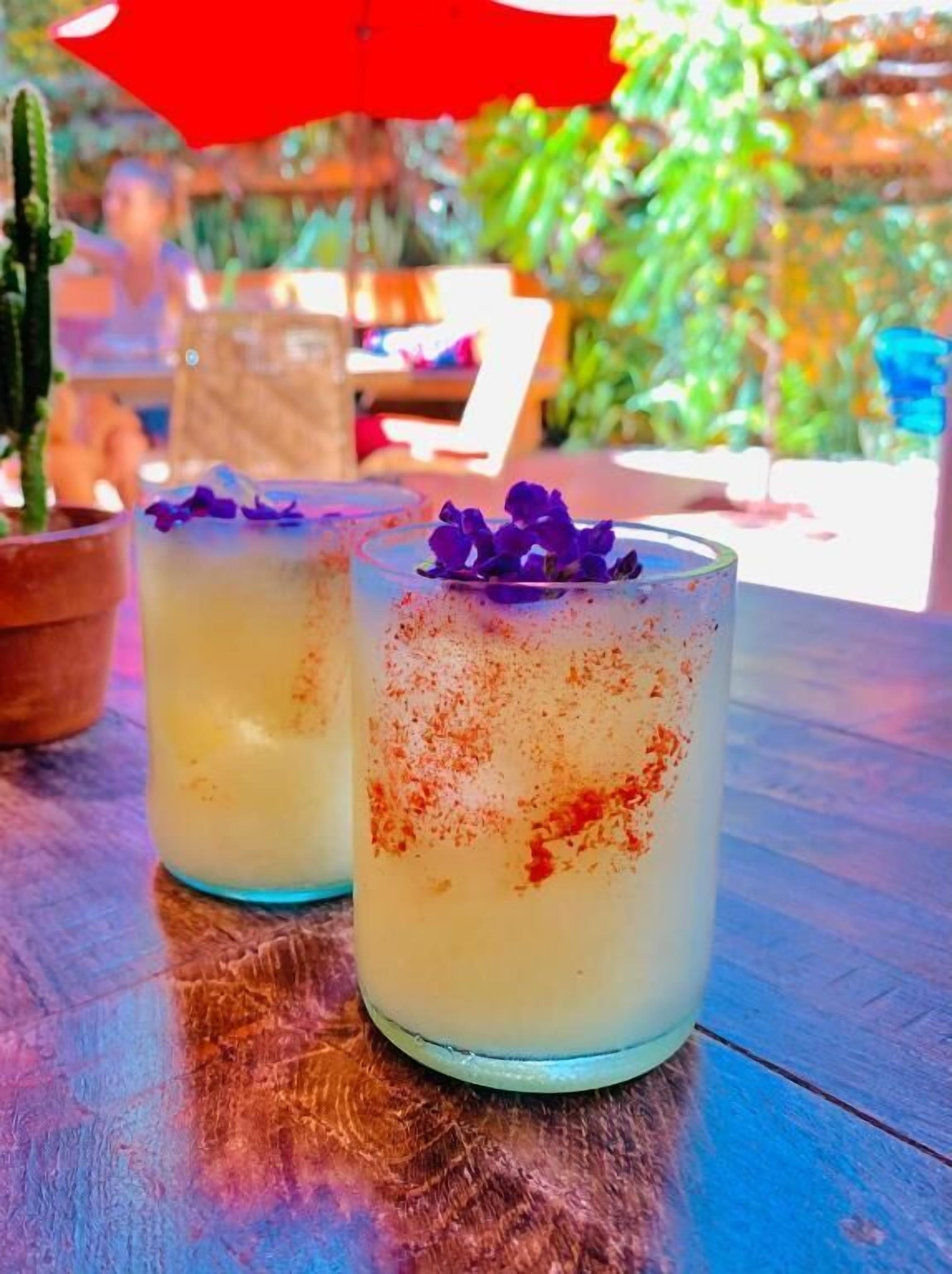 Two glasses of a beverage with a garnish on a wooden table.