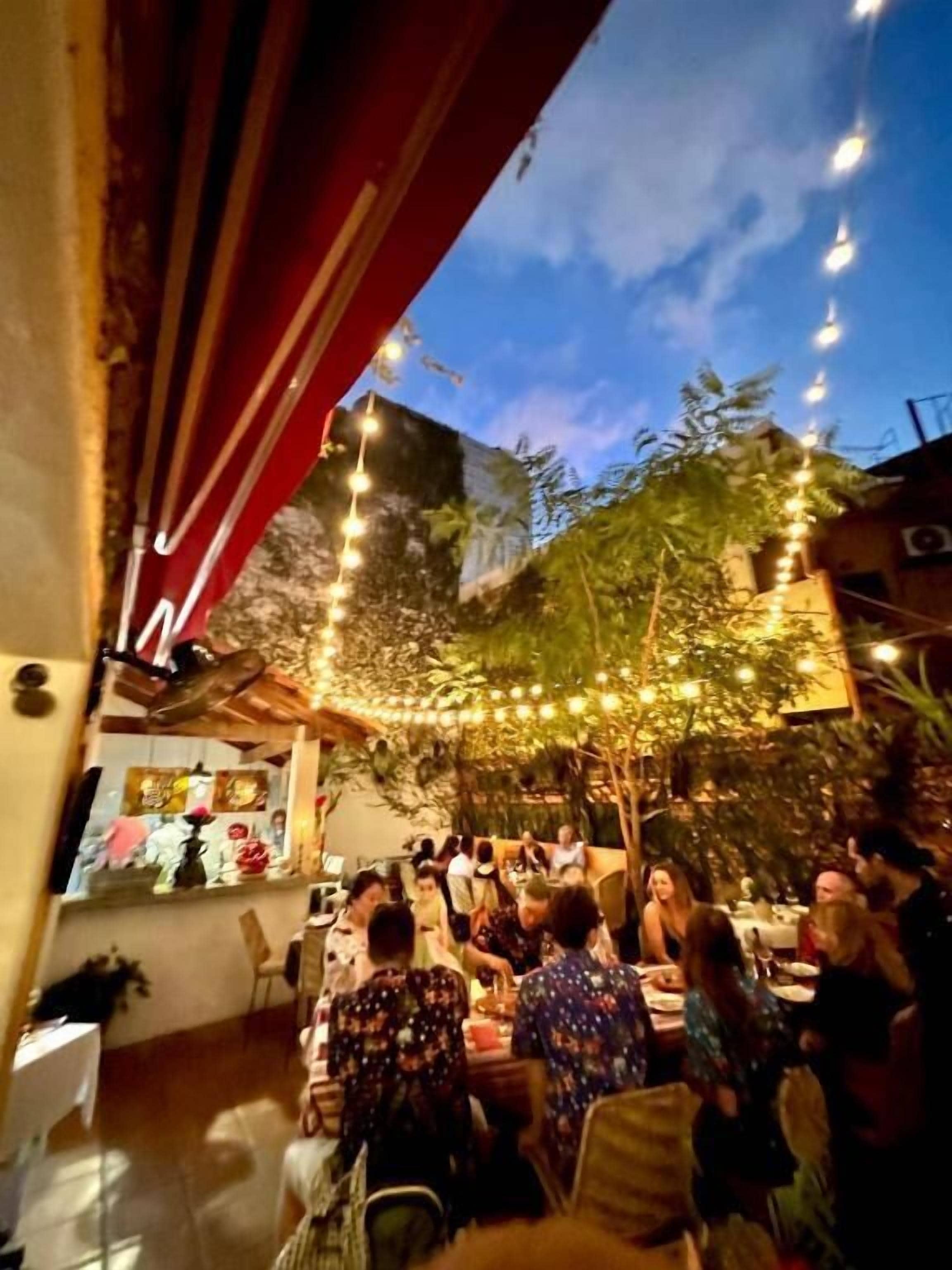 Een terras met eettafels, stoelen en sfeerverlichting.