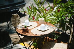 Una mesa redonda de madera con dos platos blancos, una pequeña planta en maceta y una vela.