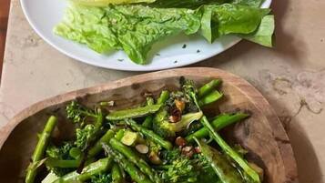 Un plato de lechuga fresca y un cuenco de madera con brócoli cocido.